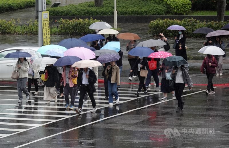 圖為台北市南港軟體園區上班族撐傘過馬路。(中央社檔案照片)
